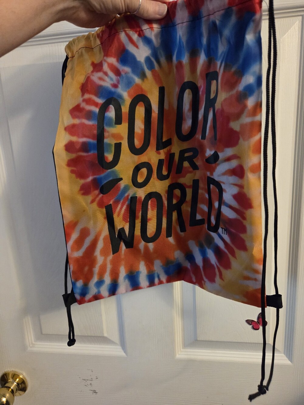 Draw string backpack with a tie dye front print that reads color our world